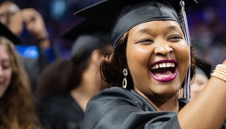A graduate enthusiastically applauding during their graduation ceremony
